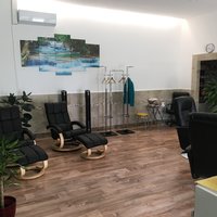 Innenperspektive des Massagestudios, in welchem eine Sitzreihe und Grünpflanzen stehen