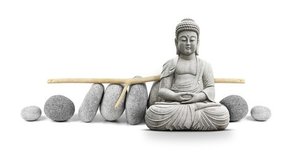 Meditierende Buddha aus Stein mit runden Steinen im Hintergrund